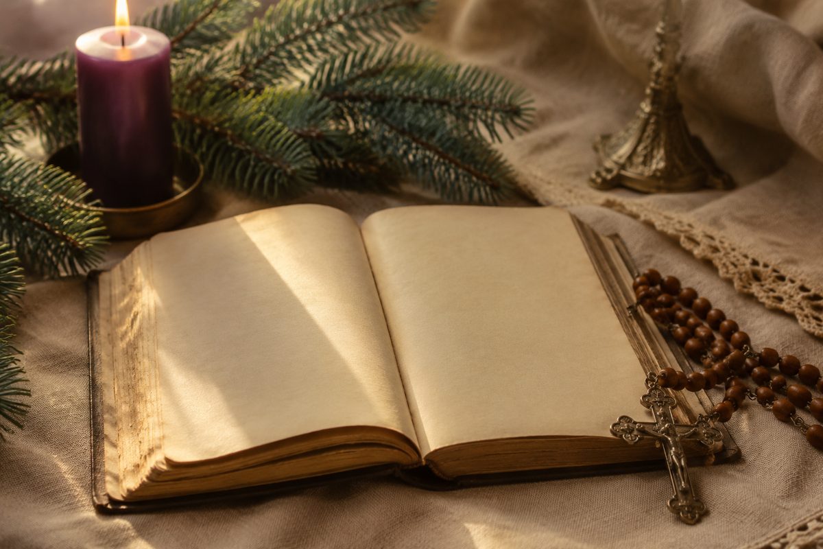 Otwarty modlitewnik, zapalona świeca roratnia i różaniec — religijny adwent